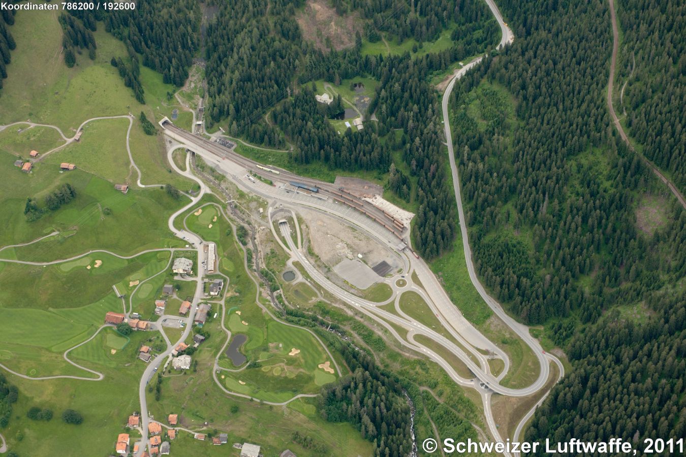 Klosters: Autoverlad Selfranga, Position: 2'786'179.43, 1'192'659.16 : Bahnatunnel Vereina gegen links oben im Bild. Strasse gegen den obern Bildrand: Klosters-Davos; Bahnlinie im Wald rechts: RhB nach Davos-Wolfgang. Unten Bildmitte: Golfplatz. Häusergruppe daneben: Läusüggen.